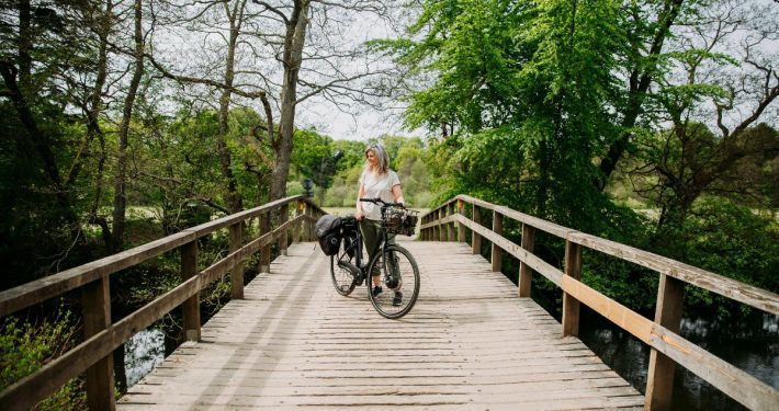 kvinde med cykel på bro